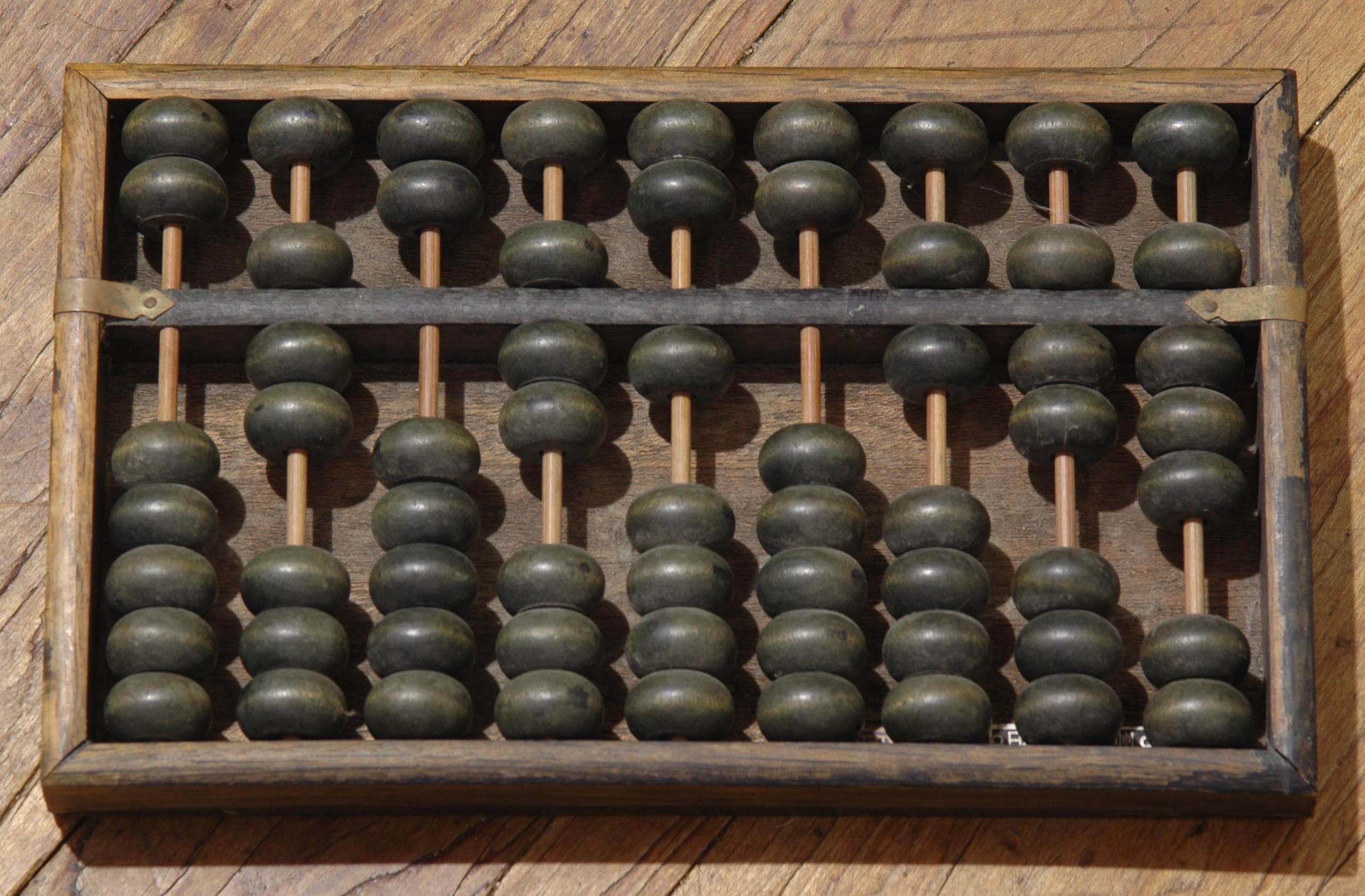 A Chinese suanpan — the thirteen-rod abacus with two beads above and five below the reckoning bar on each column. Each column holds a decimal place; each bead counts one or five, depending on which side of the bar it sits. The device is unambiguous — the count is whatever the beads say — but the user still has to agree in advance which bead is a one and which is a five, which side of the bar means "counted" and which means "set aside." On Oct 8, 2026 the Financial Times reported that OpenAI told investors its annualized revenue at the end of September was near $50 billion, about $20 billion below the figure other outlets had been publishing. The $20 billion was in the convention. OpenAI, unlike Anthropic, does not include revenue from models sold through AWS and Google Cloud. Anthropic does. The beads were the same.