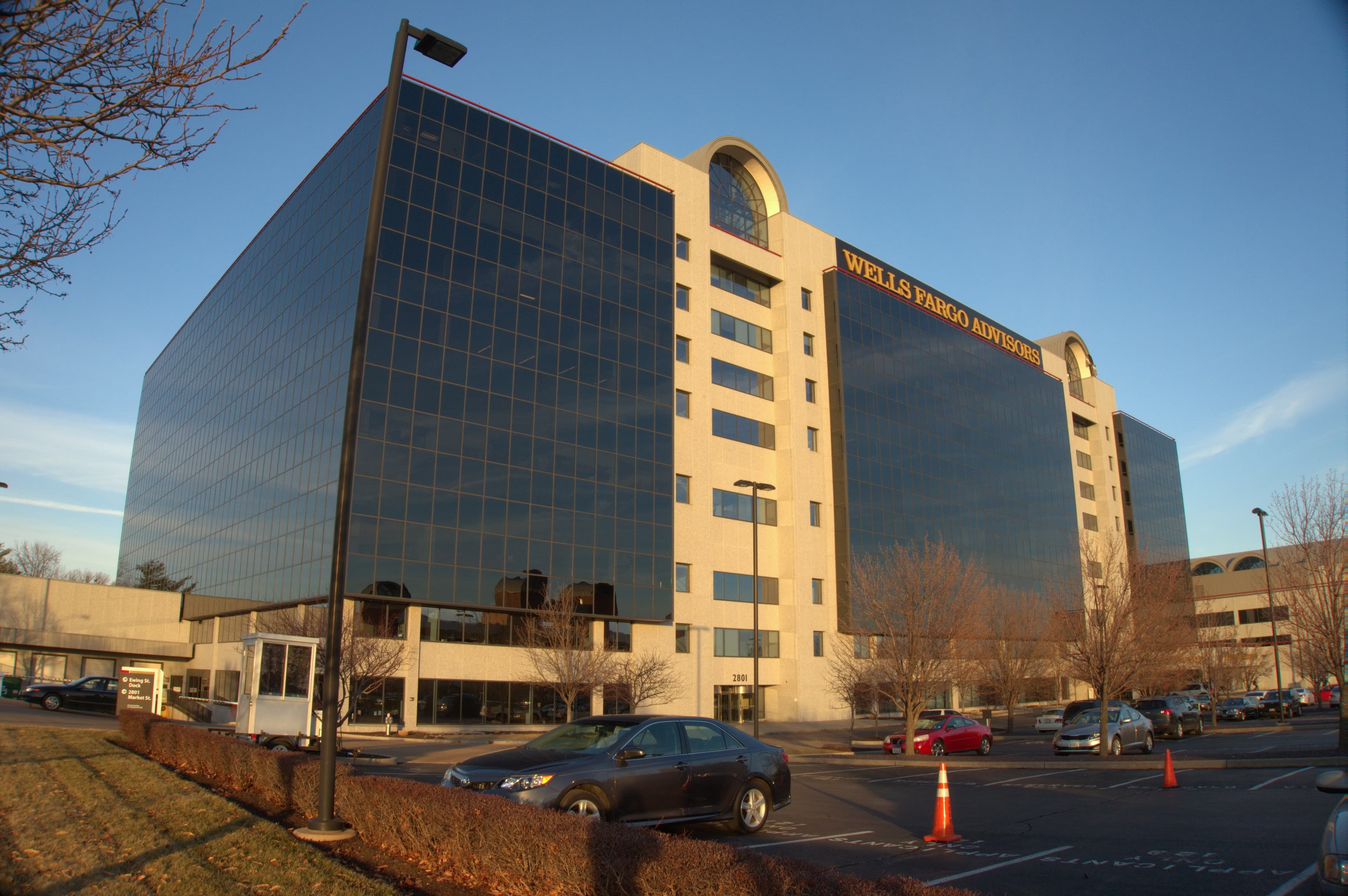 A colour photograph of the Wells Fargo Advisors headquarters tower in St. Louis, Missouri, taken from ground level in early 2014. A tall postmodern glass-and-limestone office building rises against a clear winter sky, the Wells Fargo wordmark visible at the crown. Wells Fargo is one of ten enterprises Anthropic named as design partners on its Sept 1 2026 announcement of Enterprise Frontier Safeguards — a data-custody architecture in which activity logs from Claude usage are stored not in Anthropic's systems but in the customer's own Amazon S3, Azure Blob Storage, or Google Cloud Storage account, under the customer's encryption keys and access policies, with automated cross-session pattern matching for misuse running against that customer-side data and signals sent to the customer without any Anthropic employee review. Wells Fargo's Chief Information Security Officer Munish Kumar Sharma provided the launch quote, saying the arrangement lets the bank's teams put frontier models to work while meeting its obligations to customers, employees, and regulators.