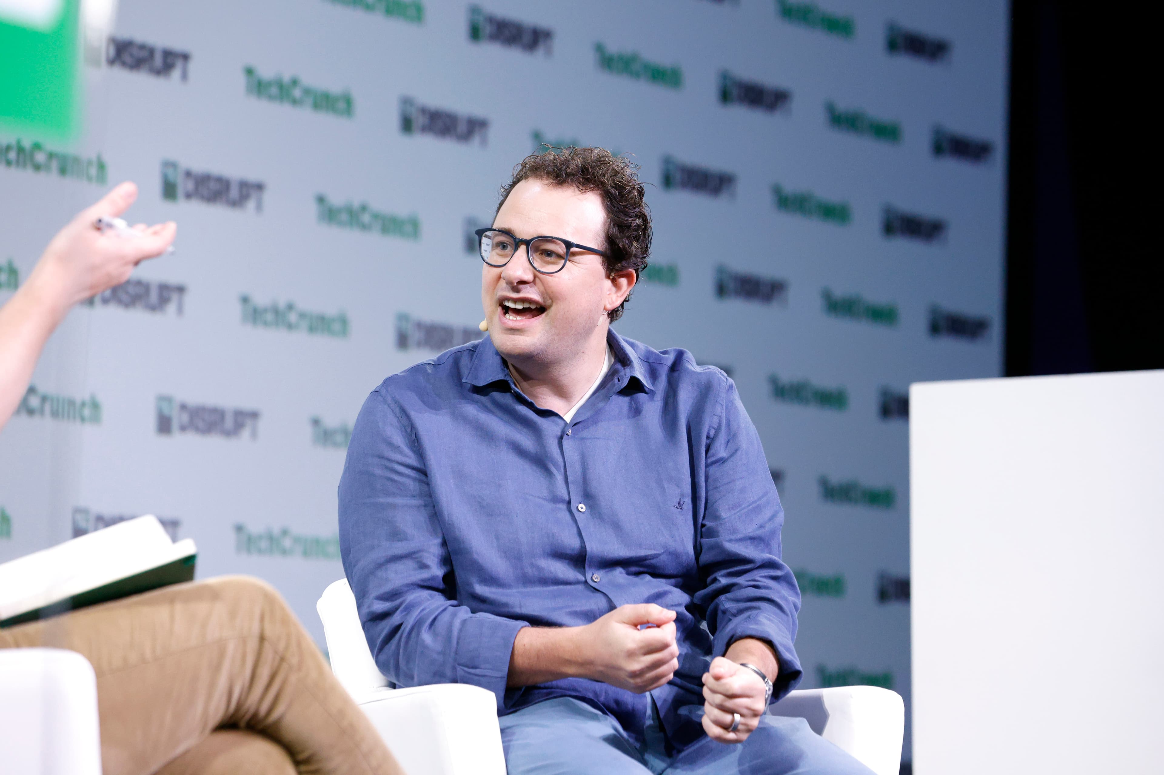 A colour photograph of Dario Amodei, co-founder and CEO of Anthropic, on stage at TechCrunch Disrupt 2023. On October 27, 2026, the US General Services Administration announced that its OneGov agreement with Anthropic has been rewritten to a token-metered contract — a 40% discount on consumption pricing for every Claude model available to government, no minimum spend, open to federal, state, local, tribal and territorial agencies.