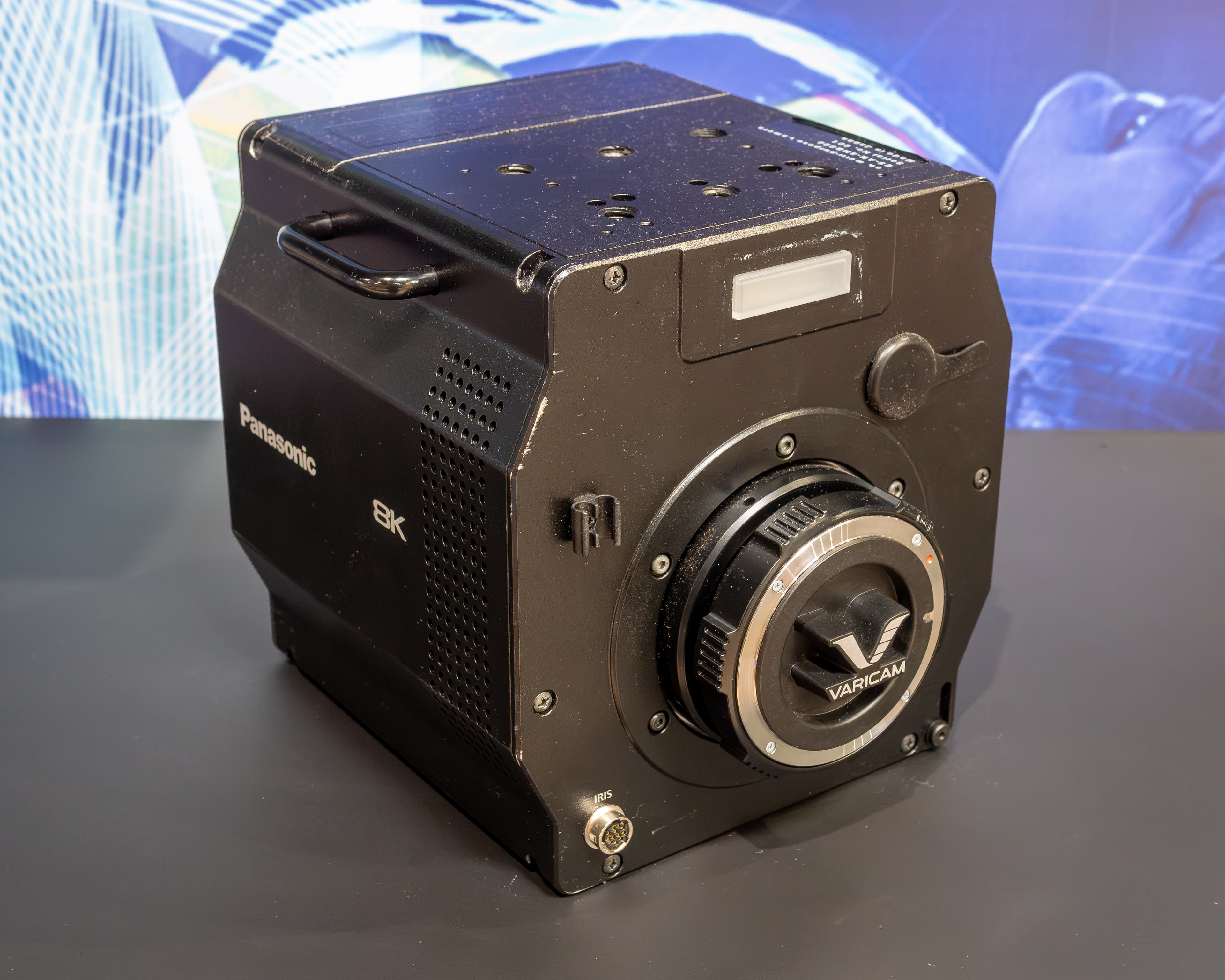 A colour photograph of a Panasonic Varicam AK-SHB800/810 professional cinema camera on a stand, dark grey body with lens mount and viewfinder attached, photographed against a plain studio backdrop in Ottobrunn, Germany, April 2025. On July 17, 2026, Netflix disclosed in its Q2 10-Q that it paid $587 million in cash for InterPositive, the post-production AI startup Ben Affleck co-founded in 2022 — a model trained on the "production dailies" a camera like this one shoots on set, and the largest single check any streamer has written for a generative AI company. The deal closed in March; the number sat on the tape for four months.