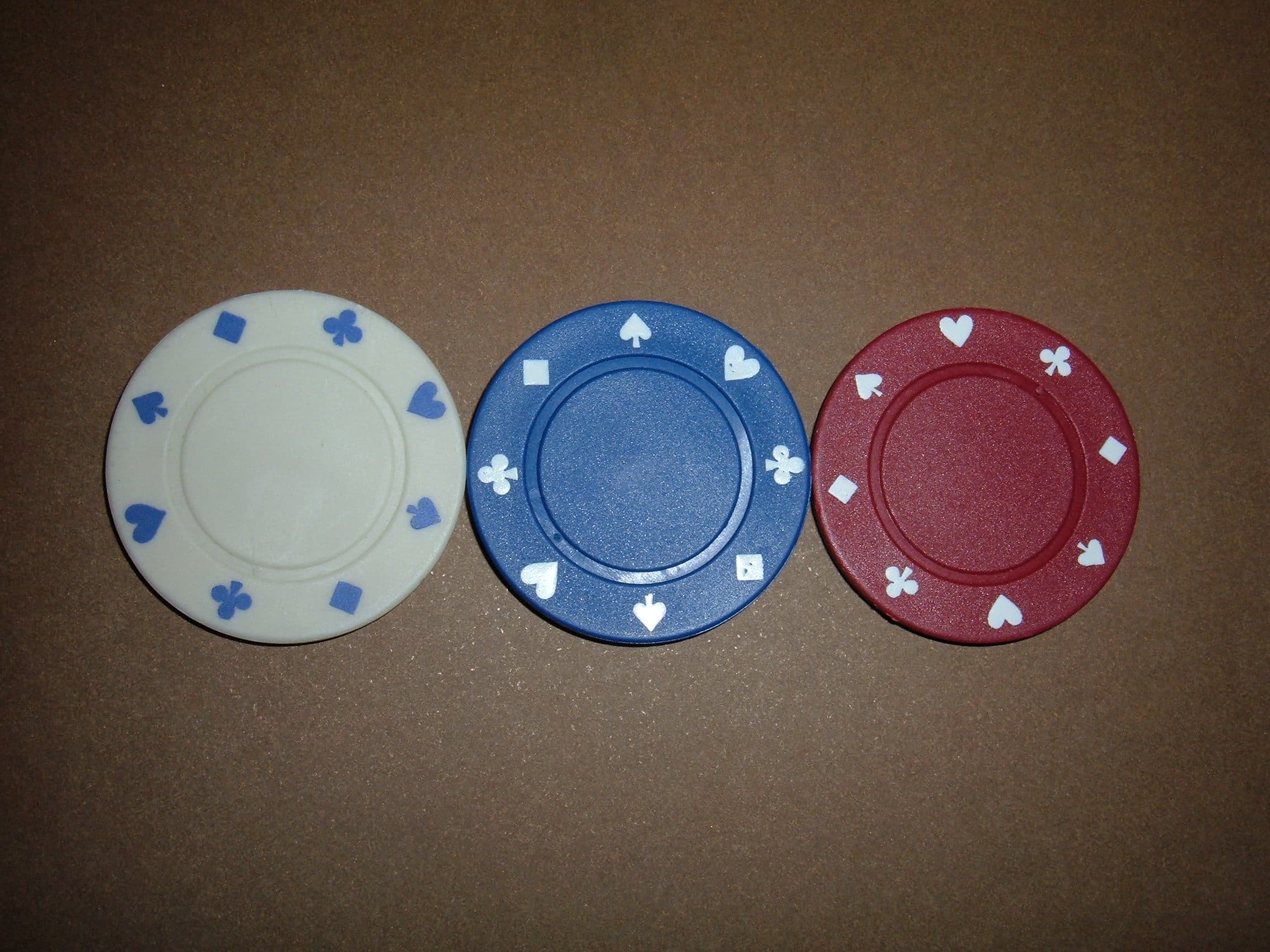 Three individual poker chips of different colours photographed against a plain background.