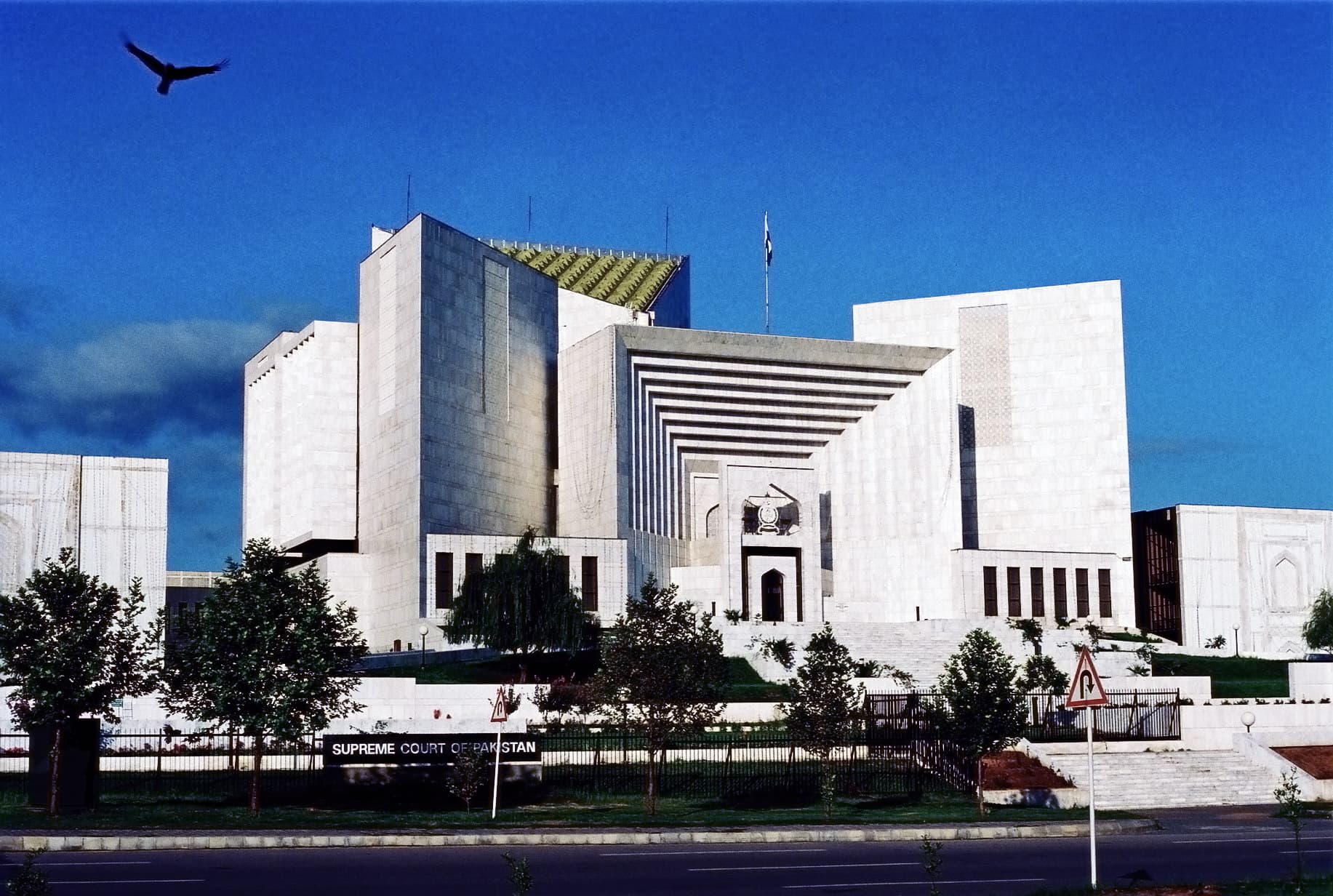 A colour photograph of the Supreme Court of Pakistan building in Islamabad, its curved white marble façade and colonnaded entrance, with the flag of Pakistan flying above the portico. In a working paper released on July 21, 2026, Sultan Mehmood of the New Economic School (Moscow), Christoph Goessmann and Elliott Ash of ETH Zurich reported the results of a pre-registered field experiment that randomised 1,559 Pakistani trial-court judges — roughly half the country's bench, across 118 courts — into three arms testing a GPT-4-based judicial assistant called JudgeGPT, and measured a 6.3 per cent increase in cases resolved that concentrated almost entirely in the arm that received targeted training on how to use the tool.