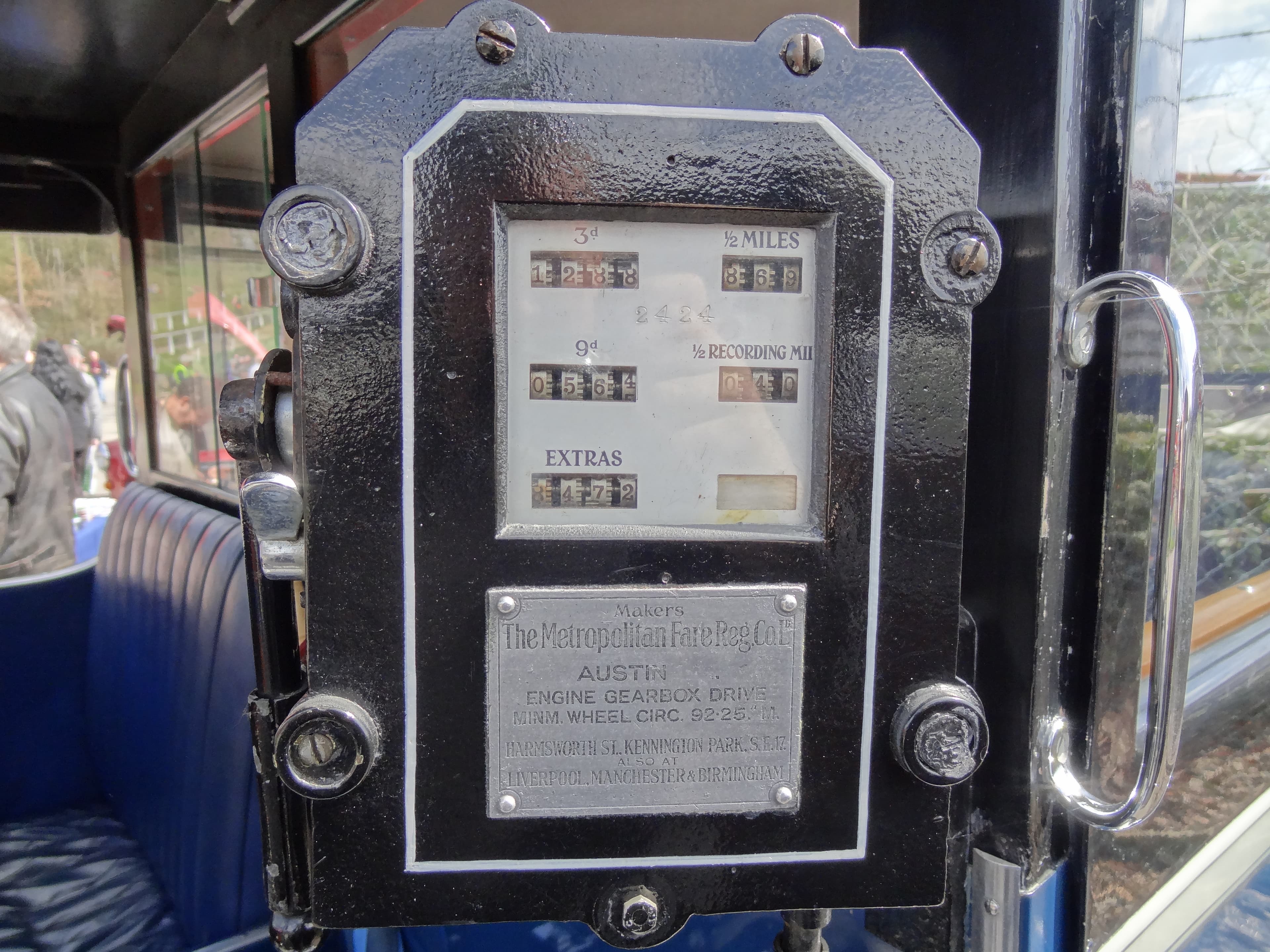A close-up of a London taxi meter mounted on a black cab dashboard, showing the fare display, tariff selector, and the "FOR HIRE" toggle, with the meter mid-fare on a metered run.