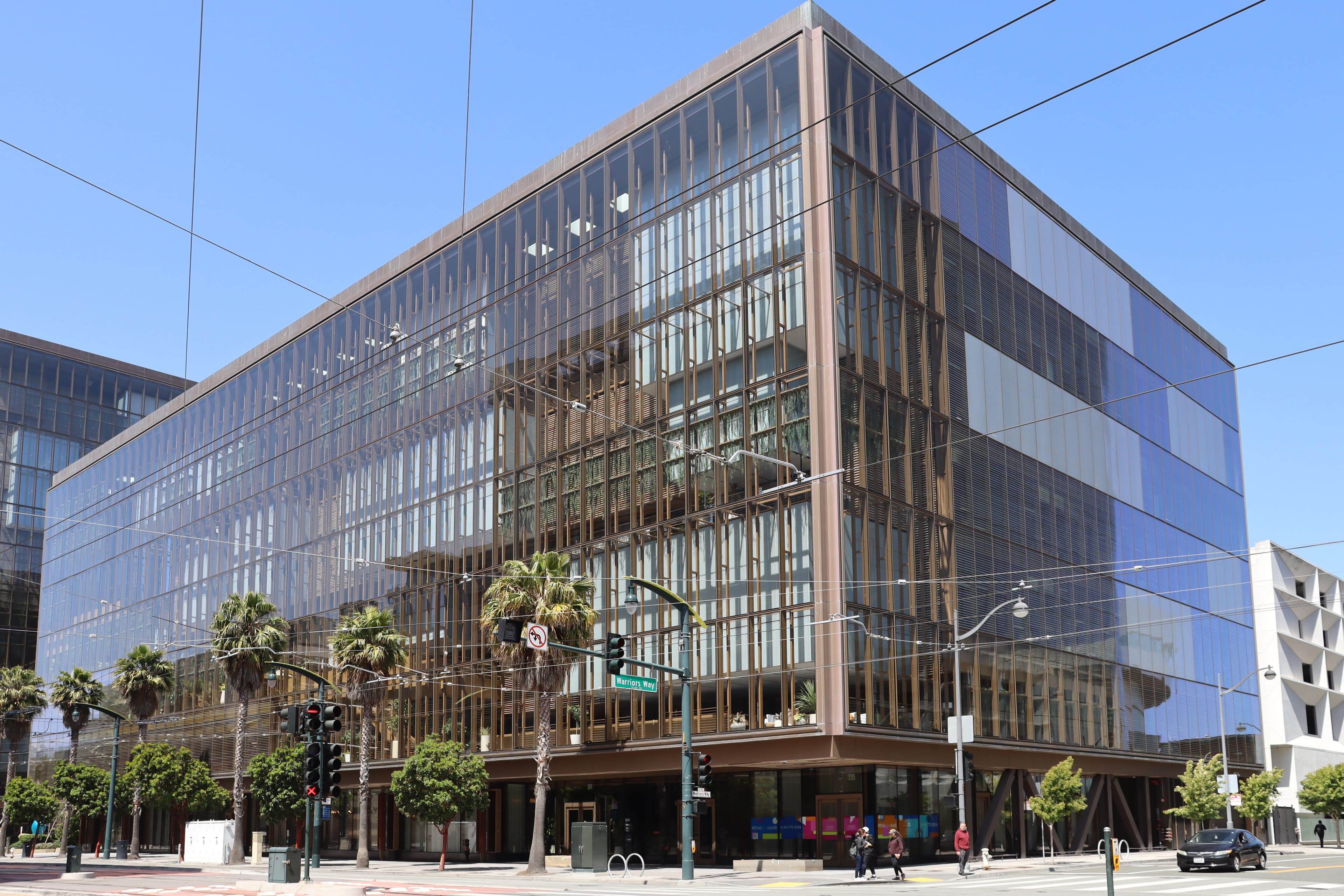 The building at 1515 Third Street in San Francisco's Mission Bay neighbourhood, photographed in June 2025 — a modern mid-rise glass-and-concrete office block on a wide low-traffic boulevard, with parked cars in the foreground and the Mission Bay tree canopy stretching along the sidewalk. The building is part of the campus from which OpenAI manages its San Francisco operations, including the OpenAI Partner Network programme announced on June 14, 2026 — a $150 million commitment to train 300,000 certified consultants by the end of the year, the company's first formal global channel programme, launched eleven days after Anthropic's parallel $100 million Claude Partner Network finalised its Services Track on June 3.